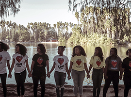 Girs holding hands wearing Love Supreme T-shirts