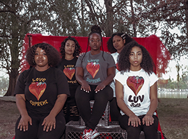 Girls sitting down wearing Love Supreme t-shirts